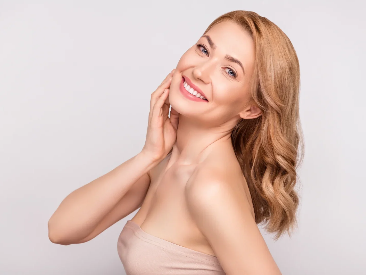 Woman with smooth facial skin touching her cheek and smiling